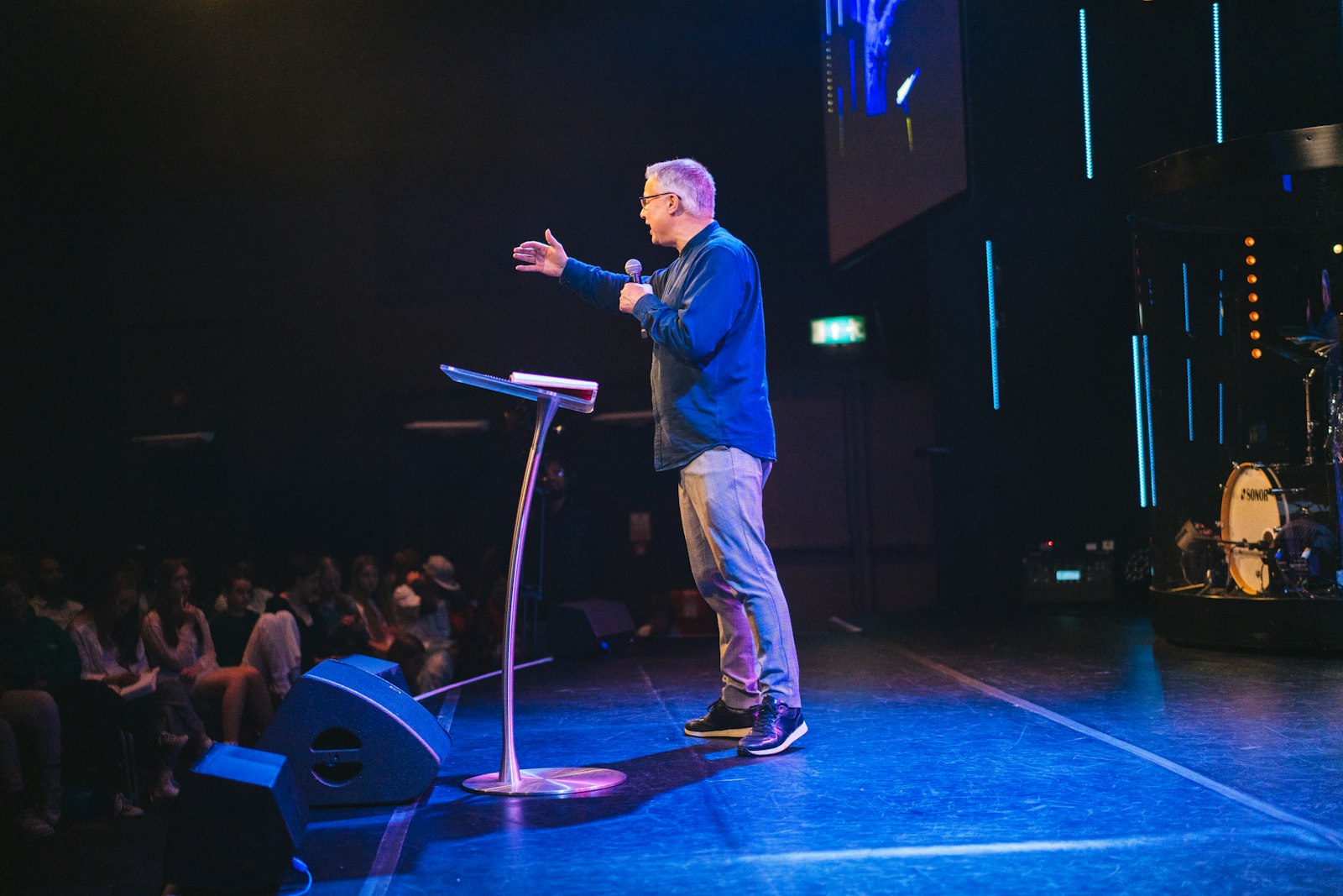 A pastor speaking on stage to a congregation